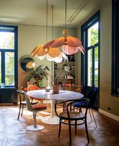 a dining room table with four chairs and a large light fixture hanging from the ceiling