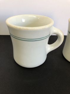 two white cups sitting next to each other on a table