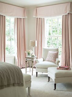 a bedroom with pink drapes and curtains on the window sill, white chair and footstool