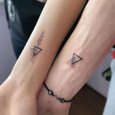 two people with matching tattoos on their arm and wrist, both holding hands in the same direction