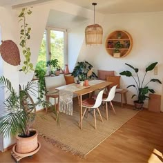 a living room filled with lots of plants next to a wooden table and white walls