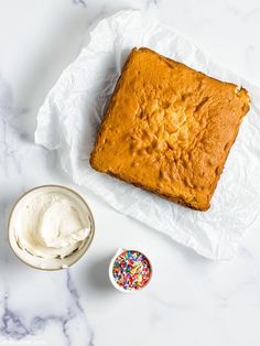 a piece of cake sitting on top of a table next to a bowl of whipped cream