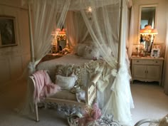 a bedroom with a white canopy bed and pink pillows on the pillowed bedspread