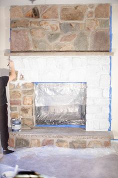 a man is painting a brick fireplace with blue tape