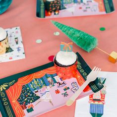 cupcakes and forks on a pink table cloth with decorations in the shape of trees