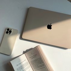 an open book sitting next to an apple laptop