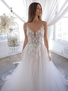 a woman in a white wedding dress standing next to a birdcage with flowers on it