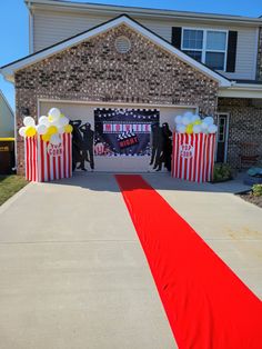 an entrance to a movie themed house with red and white striped carpet, balloons and decorations