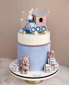 a blue and white train cake with teddy bears on the top, sitting on a table