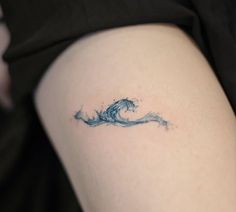 a woman's thigh with a wave tattoo on it