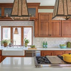 a kitchen with wooden cabinets and white counter tops, two oven hoods over the stove