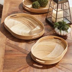 three wooden trays sitting on top of a table next to a candle and potted plant