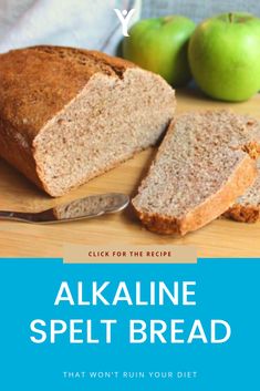 a loaf of bread sitting on top of a wooden cutting board next to green apples