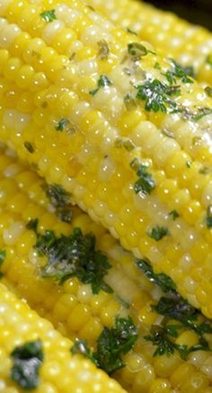 corn with parsley on the cob is shown close up in this image, it appears to be cooked or uncooked