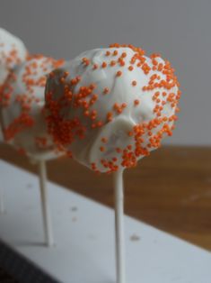 two cake pops covered in white and orange sprinkles