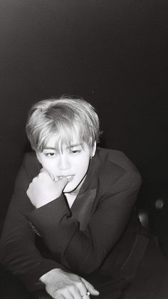 a black and white photo of a person sitting at a table with their hand on his chin