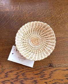 a small woven basket sitting on top of a wooden table next to a business card