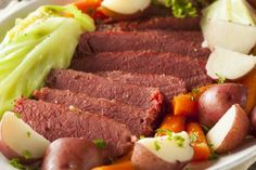 corned beef with potatoes, carrots and lettuce on a white plate