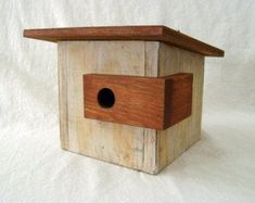 a wooden birdhouse with a hole in the roof on a white sheeted background