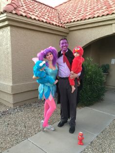 a man and woman dressed up in costumes pose for a photo with sesame street characters