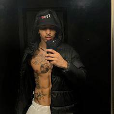 a man taking a selfie with his cell phone in front of him and tattoos on his chest