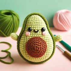 a crocheted avocado is sitting on a table next to some yarn