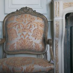 an ornate chair sits in front of a fireplace