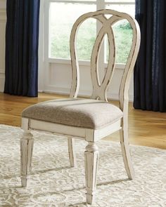 a white chair sitting on top of a rug in front of a window with blue curtains