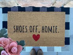 a door mat that says shoes off homie with a heart on it next to a pink flower