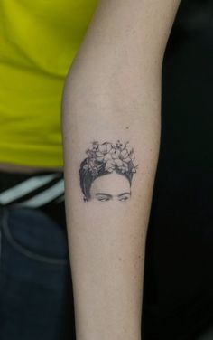 a woman's arm with a tattoo on it that has flowers in her hair