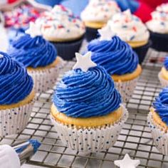 cupcakes with blue frosting and stars on them are cooling on a rack