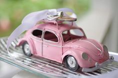 a pink toy car with a bow on the roof is sitting on a metal rack