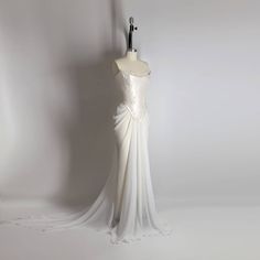 a white wedding dress is displayed on a mannequin headdress, with the back draped over