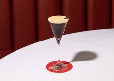 a martini glass sitting on top of a white table next to a red plate and wall