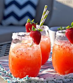 three glasses with strawberries in them sitting on a table