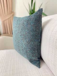 a blue pillow sitting on top of a white couch next to a potted plant