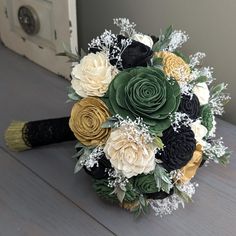 a bridal bouquet with black, yellow and white flowers on a table in front of a door