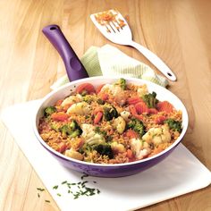 a bowl filled with rice and vegetables on top of a table next to a fork