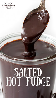 a spoon full of melted hot fudge on top of a glass jar filled with chocolate