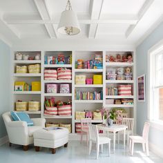 a living room filled with lots of white furniture and shelves full of colorful bookshelves