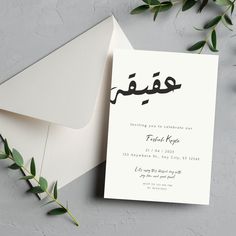 an open envelope with a white card and some green leaves