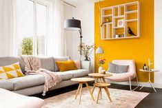 a living room with yellow walls and white furniture on the floor, including a gray couch