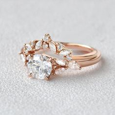 a rose gold ring with two pear shaped diamonds on the side and an oval diamond in the middle