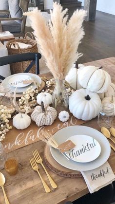 a wooden table topped with white pumpkins and other thanksgiving decorating items on top of it