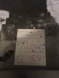 a sign that is on the side of a building with snow around it and someone's feet standing next to it