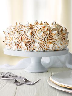 a white cake sitting on top of a table next to a plate and silverware