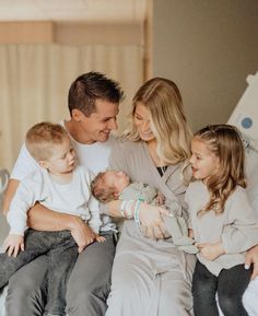 a man, woman and two children are sitting on a bed with their arms around each other