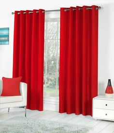 a living room with red curtains and white furniture