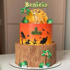 a birthday cake decorated with the lion king and jungle animals is on top of a tree stump