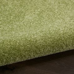 a close up view of a green rug on a wooden floor